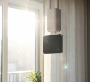 Motor SwitchBot instalado com seu painel solar recebendo luz direta da janela para recarga automática.