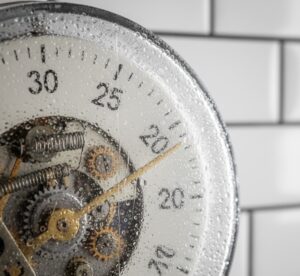 Close-up de um timer mecânico com gotas de condensação, ilustrando como a umidade afeta o equipamento.